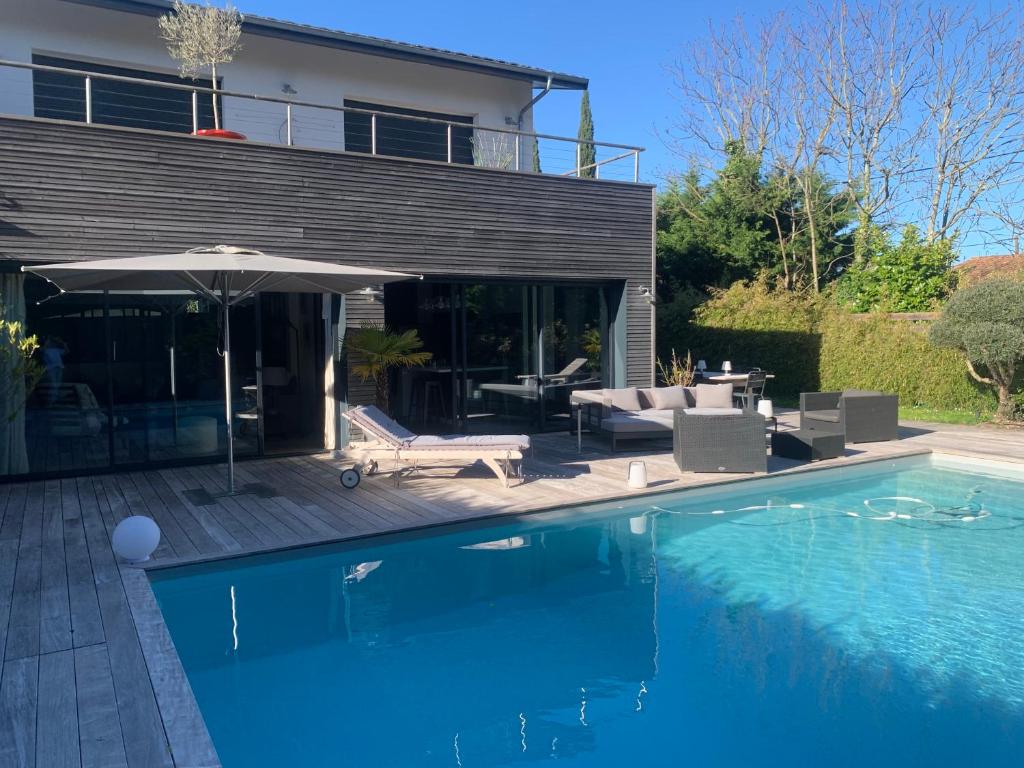 une maison avec une piscine et un parasol dans l'établissement Villa Soleil Bordeaux 4 chambres, à Le Bouscat