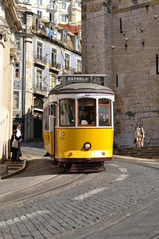 a yellow trolley car driving down a city street at Santa Justa Bedrooms in Lisbon