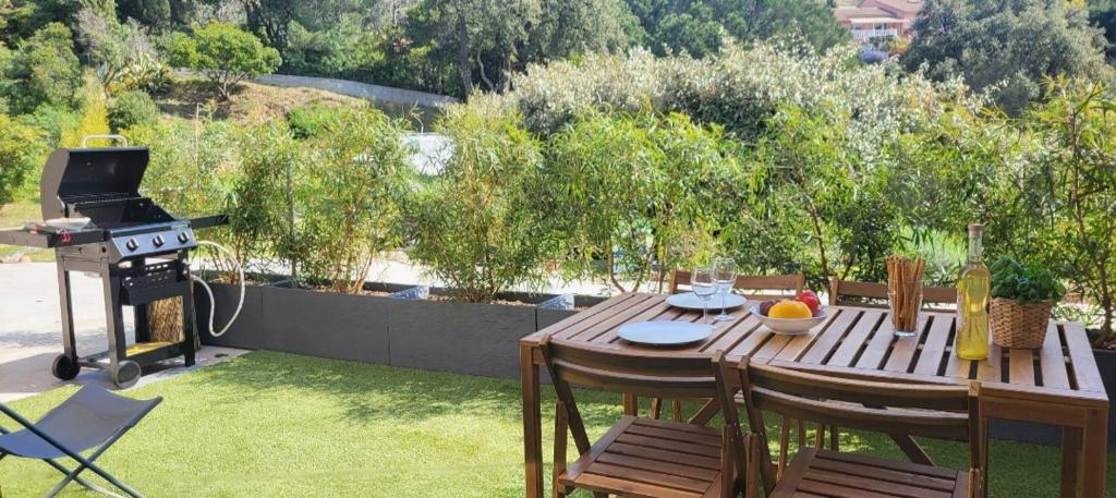 - une table en bois avec des chaises et un barbecue dans la cour dans l'établissement Studio nature, à La Londe-les-Maures