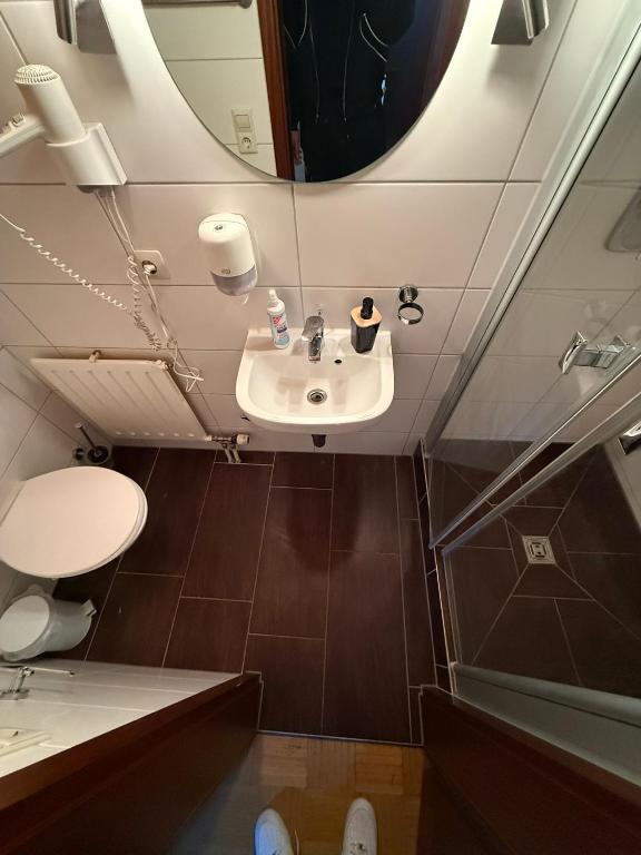 ein Badezimmer mit Waschbecken, Toilette und Spiegel in der Unterkunft Zum Griechen Restaurant und Pension in Forchtenberg