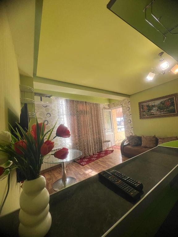 a living room with a table and a vase with flowers at SWEET APARTMENT KUTaISI in Kutaisi