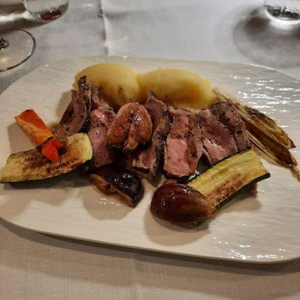 a plate of meat and vegetables on a table at Locanda Gaudemus Boutique Hotel in Sistiana