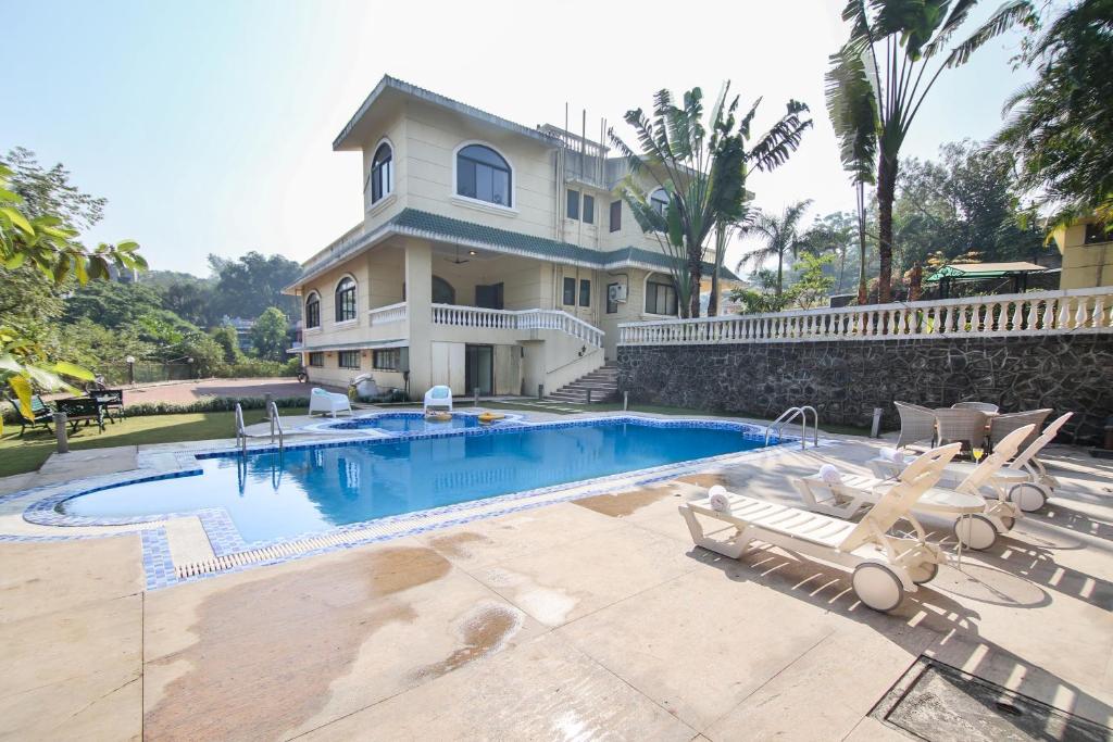 una casa con piscina e due sedie a sdraio di Akbar Villa Spacious 4BHK Grand Pool at TranqVillas a Lonavala