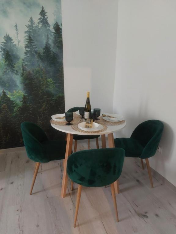 een tafel met vier groene stoelen en een fles wijn bij Apartament Górskie Zacisze in Szklarska Poręba