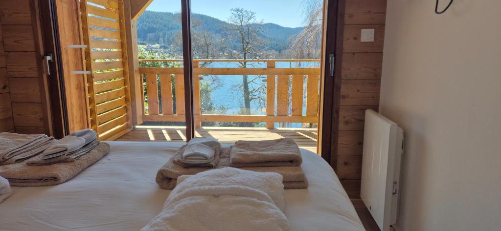 a bedroom with a bed with towels and a large window at L'Or du Lac in Gérardmer