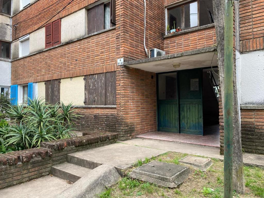 a brick building with a green door and stairs at Petit Olimar in Treinta y Tres