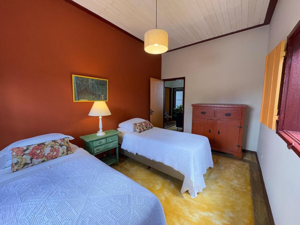 - 2 lits dans une chambre aux murs orange dans l'établissement Cores da Mata - Casa de Charme, à Tiradentes