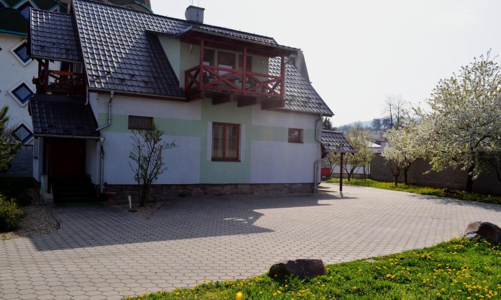 ein weißes Haus mit einem roten Balkon auf einer Auffahrt in der Unterkunft Villa Silver Green in Žarnovica