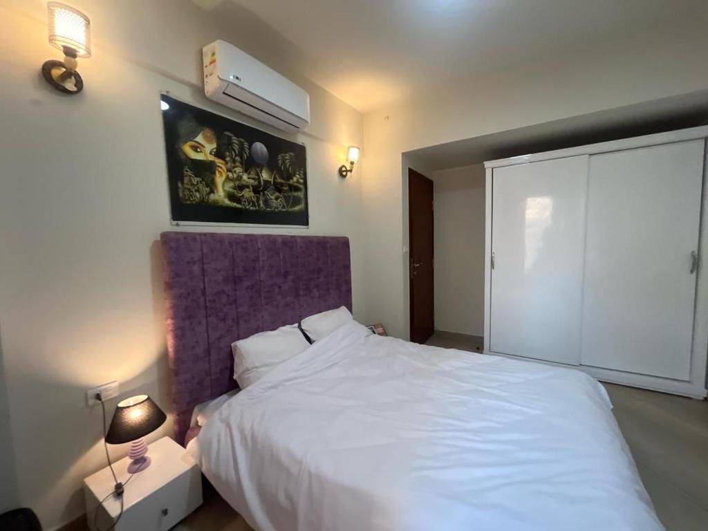 a bedroom with a white bed with a purple headboard at princess Resort Hurghada in Hurghada