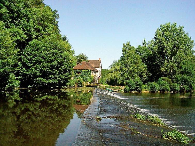 una casa sulla riva di un fiume con una casa di Willow Cottage a Saint-Hilaire-sur-Bénaize