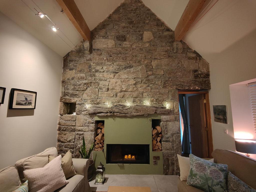 a living room with a stone wall with a fireplace at The Burren, Cozy Cottage, County Clare in Carran