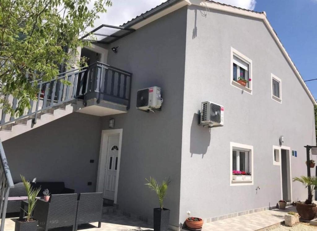 a white house with a staircase and a balcony at Apartman Đokić 3 in Bale