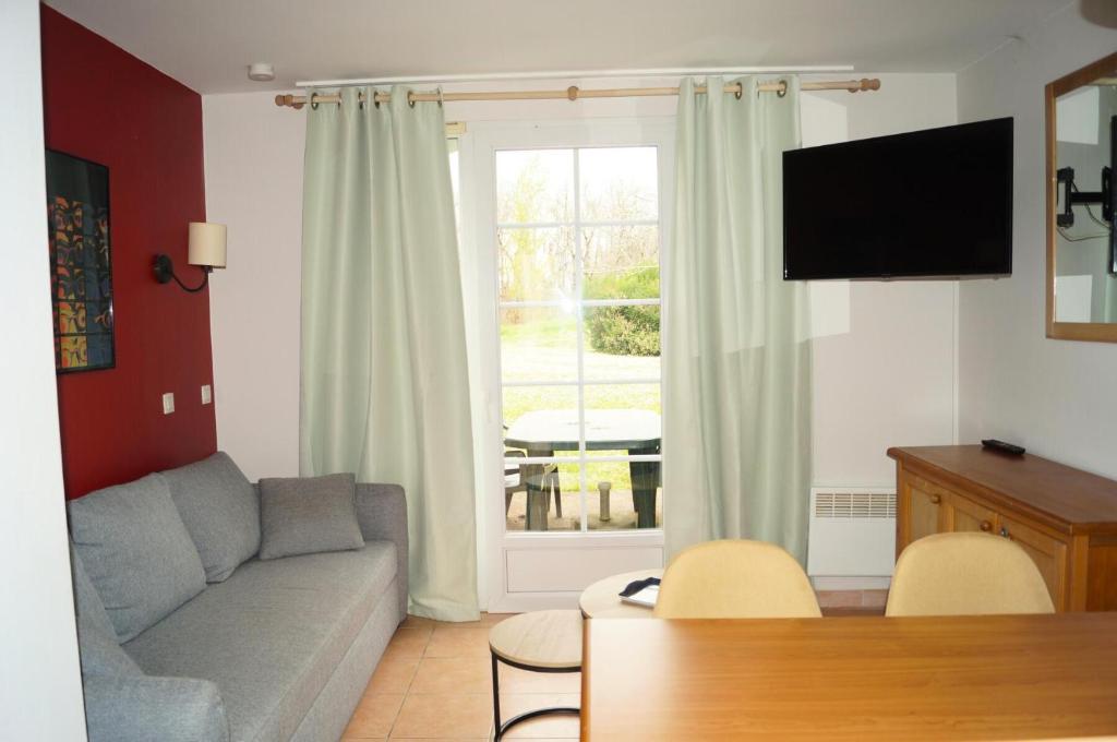 un salon avec un canapé et une fenêtre dans l'établissement La résidence du Lac - maeva Home - Maison 3 pièces 6 personnes - Sélection MAE-0364, à Monflanquin