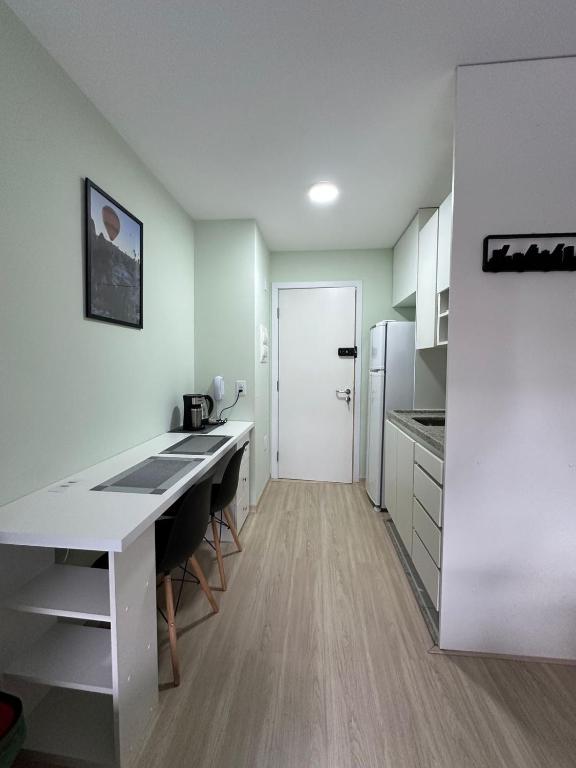 a kitchen with a white desk and a white refrigerator at Nari Loft in São Paulo