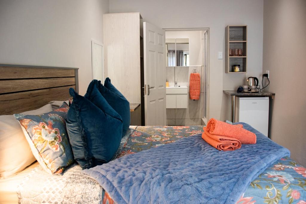 un letto con coperta blu e cuscini sopra di The Garden Manor a Winterton