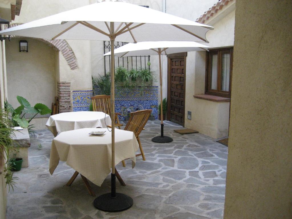two tables and chairs with umbrellas in a courtyard at Casa Rural La Botica in Oropesa