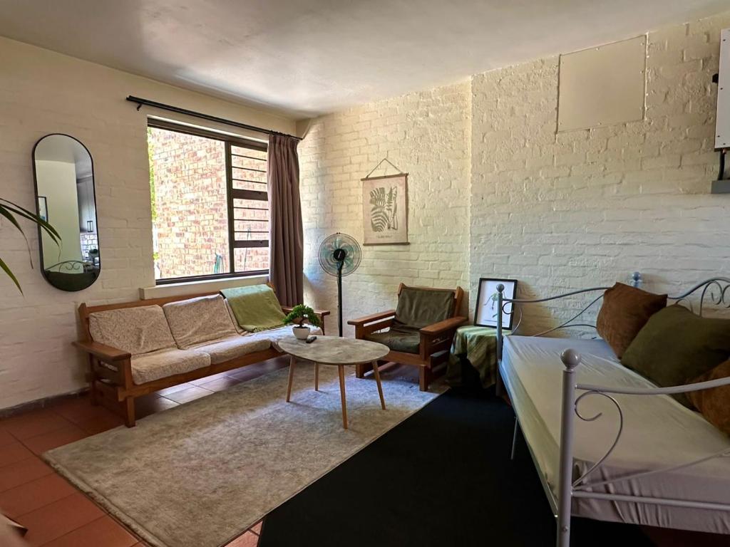 a living room with a bed and a couch and a table at Comfy full apartment in Stellenbosch