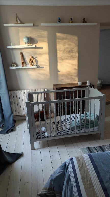 - un lit bébé dans une chambre avec fenêtre dans l'établissement Jolie maison en pierres au calme dans un charmant village aux portes de Bayeux, à Carcagny