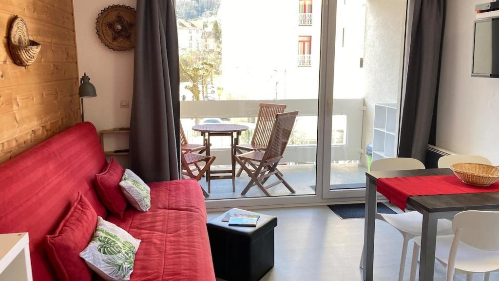 un salon avec un canapé rouge et une table dans l'établissement Appartement face aux thermes Allevard, à Allevard