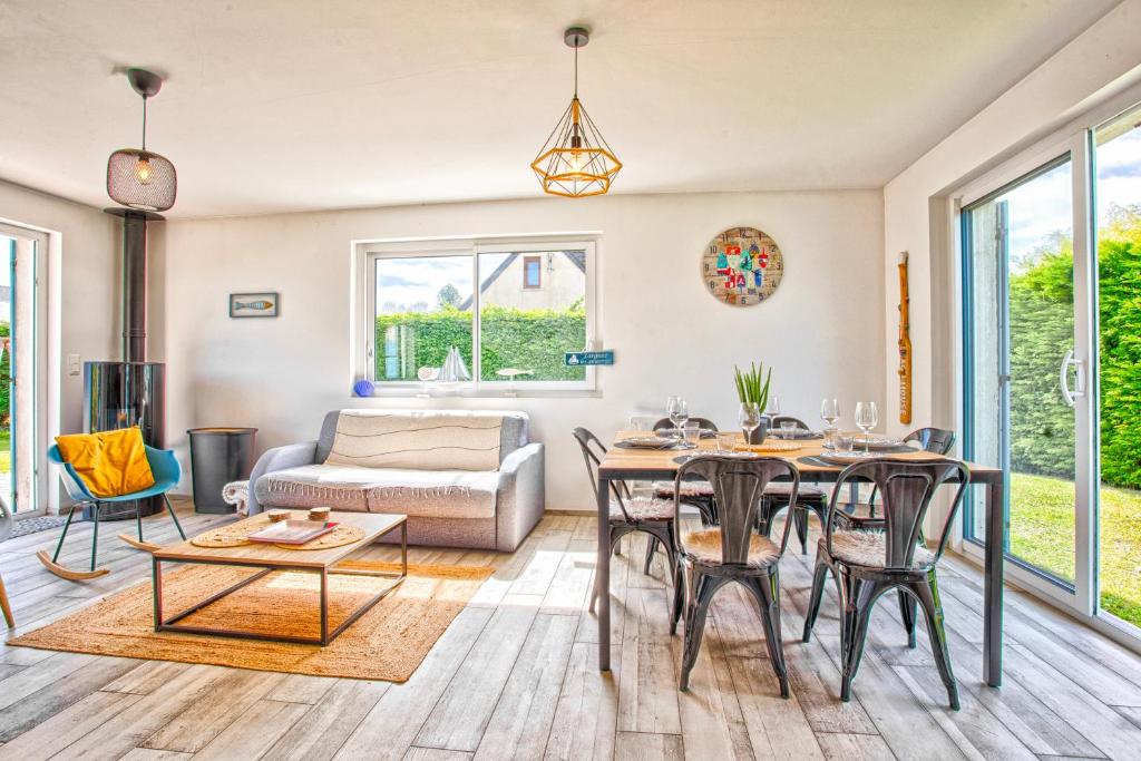 Una sala de estar con una mesa y sillas y un sofá. en L&#39;effet mer Maison rénovée lumineuse tout confort belle terrasse grand jardin clos sans vis à vis parking jeux pour enfants 5 mn à pied de la plage d&#39;Asnelles et centre bourg - proche Bayeux au coeur des plages du débarquement, en Asnelles