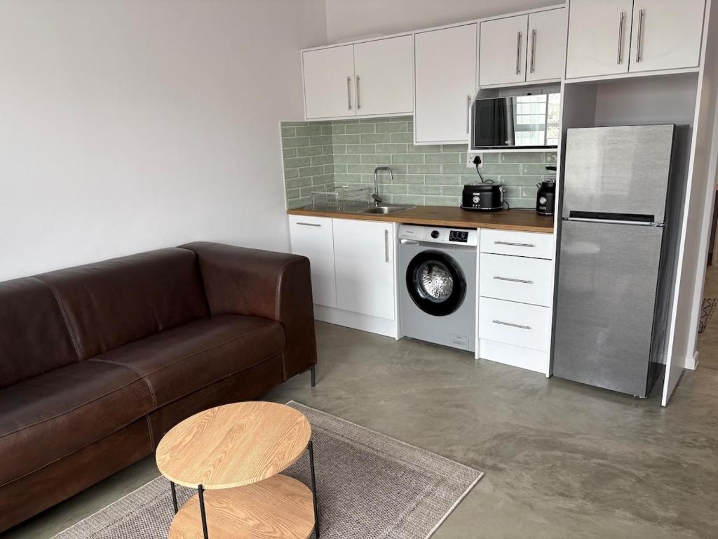 ein Wohnzimmer mit Couch und Küche in der Unterkunft Comfy Cottage in Walvis Bay