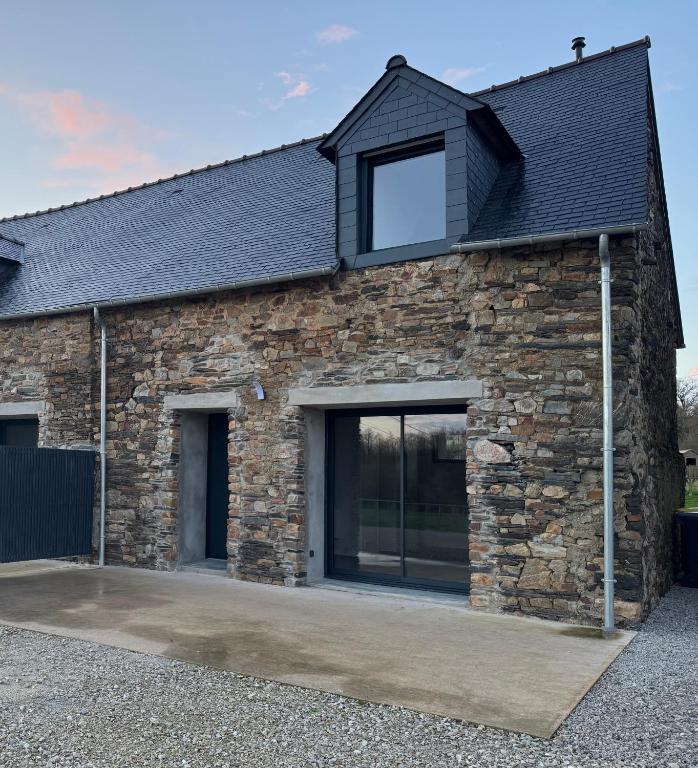 une maison en pierre avec de grandes fenêtres et un toit noir dans l'établissement Le Gîte de la vilaine, à Sainte-Anne-sur-Vilaine