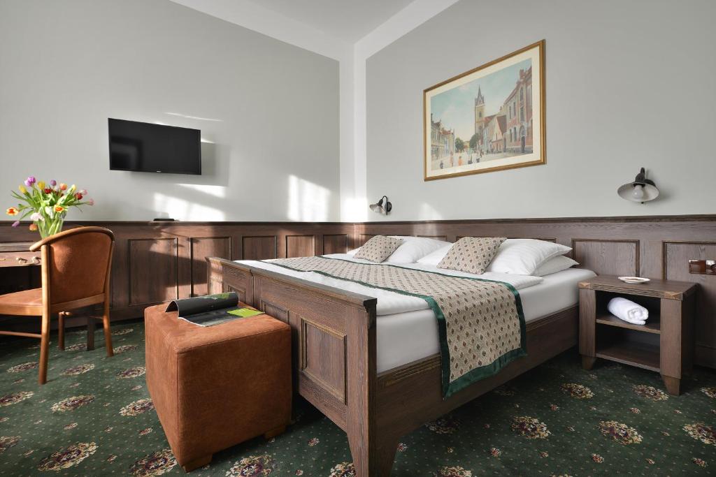 una camera da letto con un letto, una scrivania e una TV di Hotel Podhrad a Hluboká nad Vltavou
