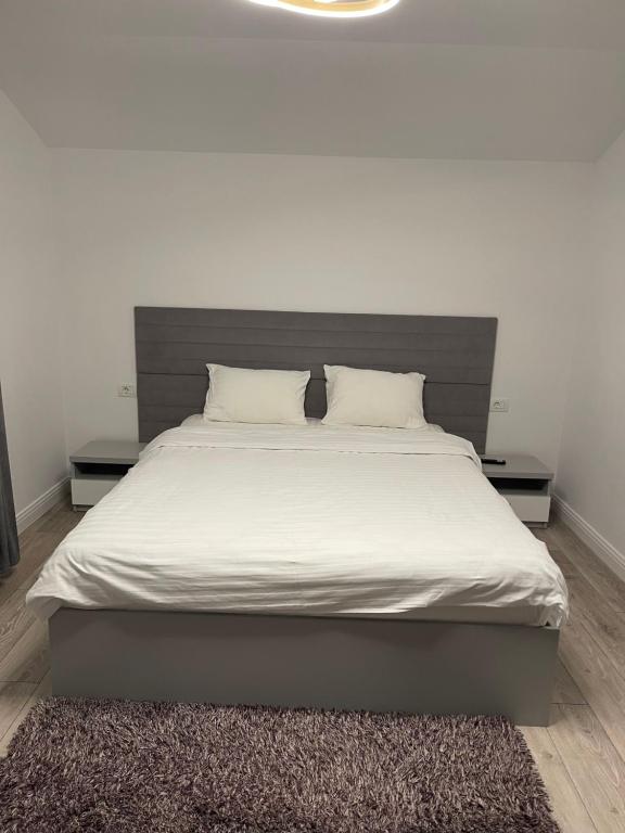 a bed with white sheets and pillows in a bedroom at Happy apartment 2 in Chiajna