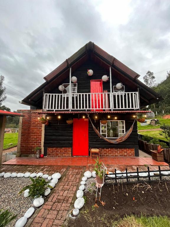 a house with a red door and a balcony at La cabaña de la abuela in Sutatausa