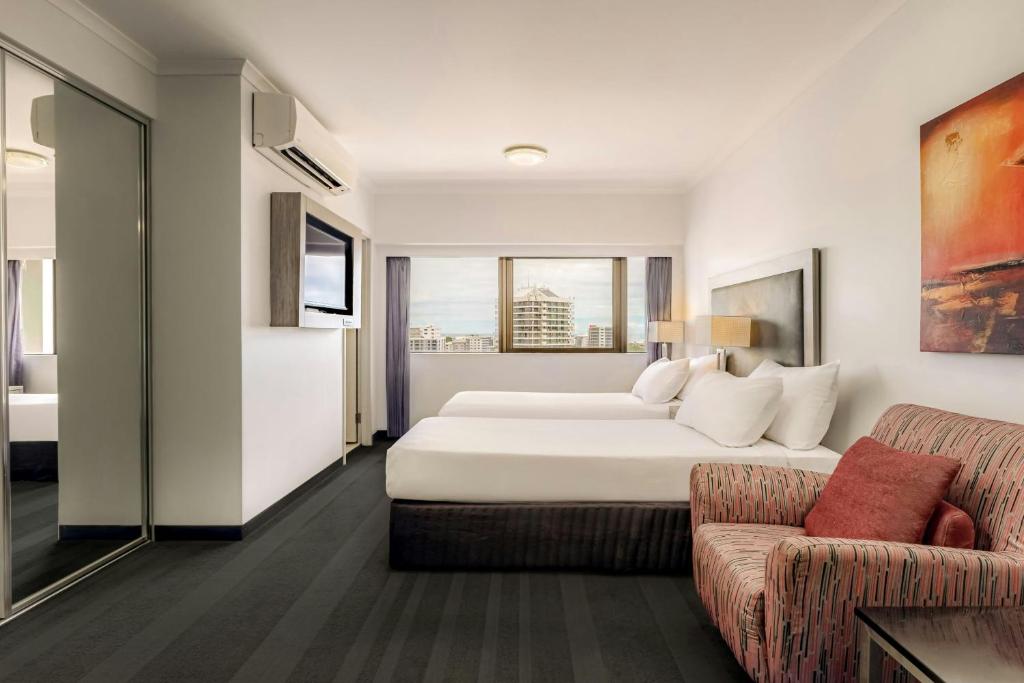 a hotel room with a bed and a couch at Courtyard by Marriott Darwin in Darwin