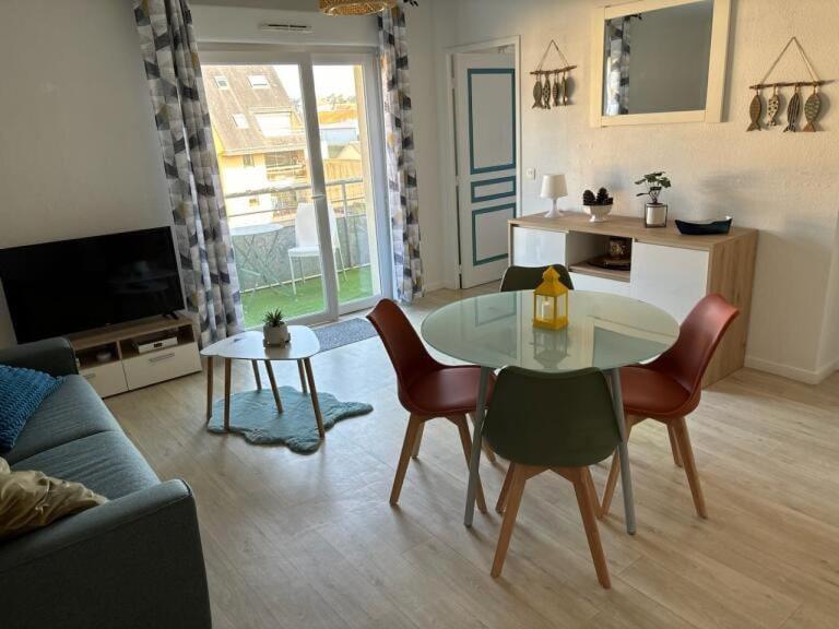 un salon avec une table et des chaises dans l'établissement Appartement avec piscine, à Grandcamp-Maisy