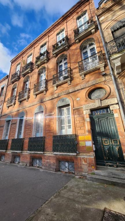 - un bâtiment en briques avec des fenêtres et une porte dans l'établissement T4 souplex Authentique Toulousain, 5Pers 3lits- Tout équipé - hypercentre, à Toulouse
