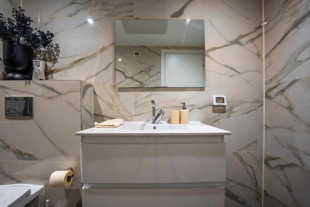 ein weißes Badezimmer mit Waschbecken und Spiegel in der Unterkunft Valencia Apartment - By Harim in Eilat