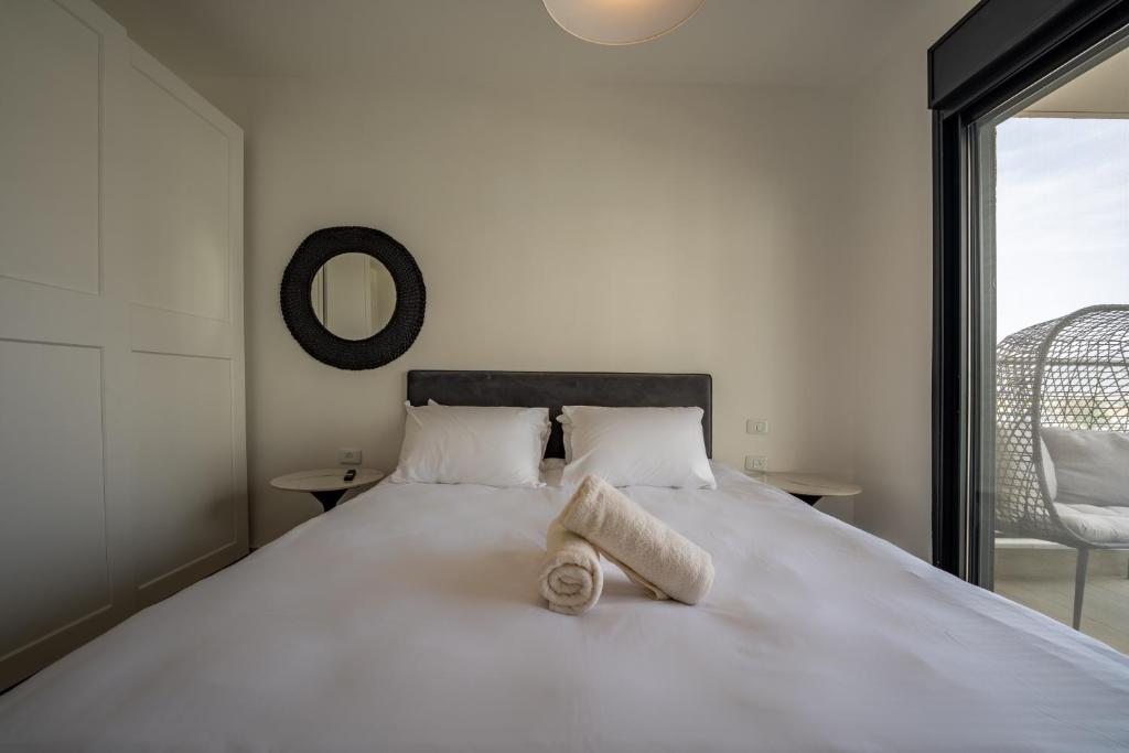 Schlafzimmer mit einem großen weißen Bett und einem Spiegel in der Unterkunft Valencia Apartment - By Harim in Eilat
