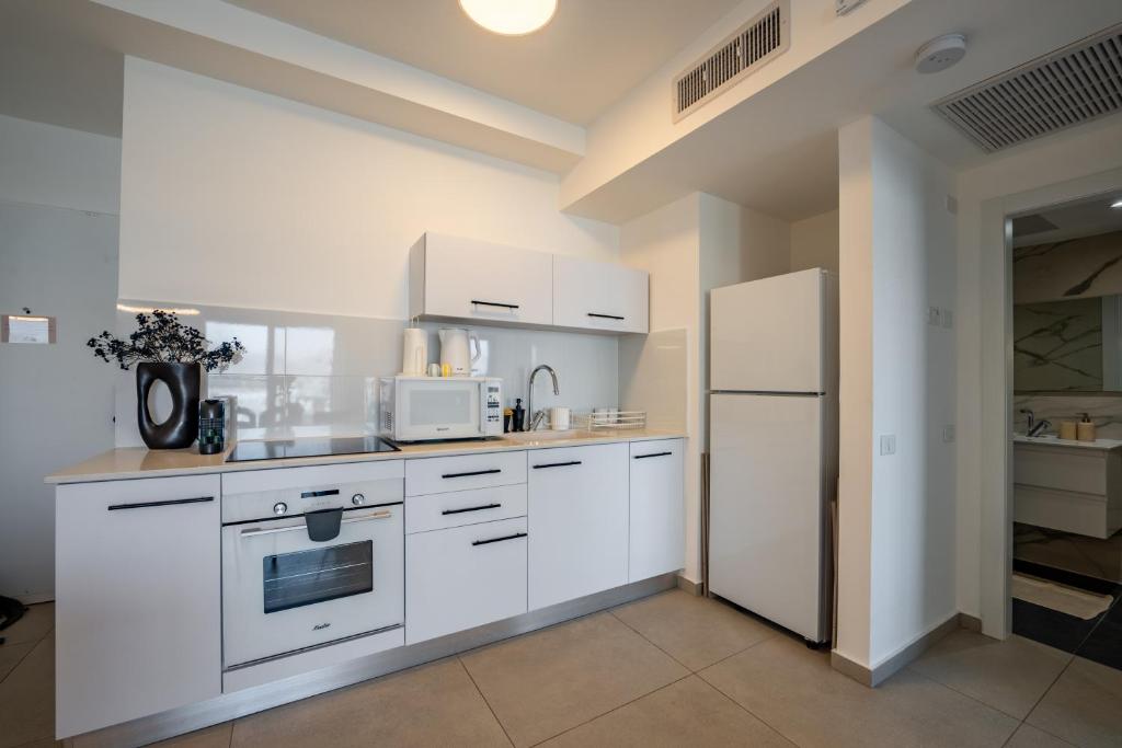 eine Küche mit weißen Schränken und einem weißen Kühlschrank in der Unterkunft Valencia Apartment - By Harim in Eilat