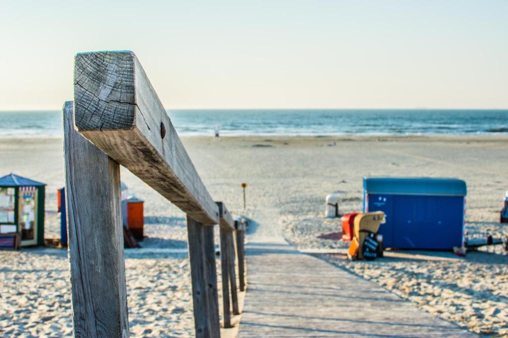a wooden boardwalk on a beach with a blue container at Hotel Atlantic Juist in Juist