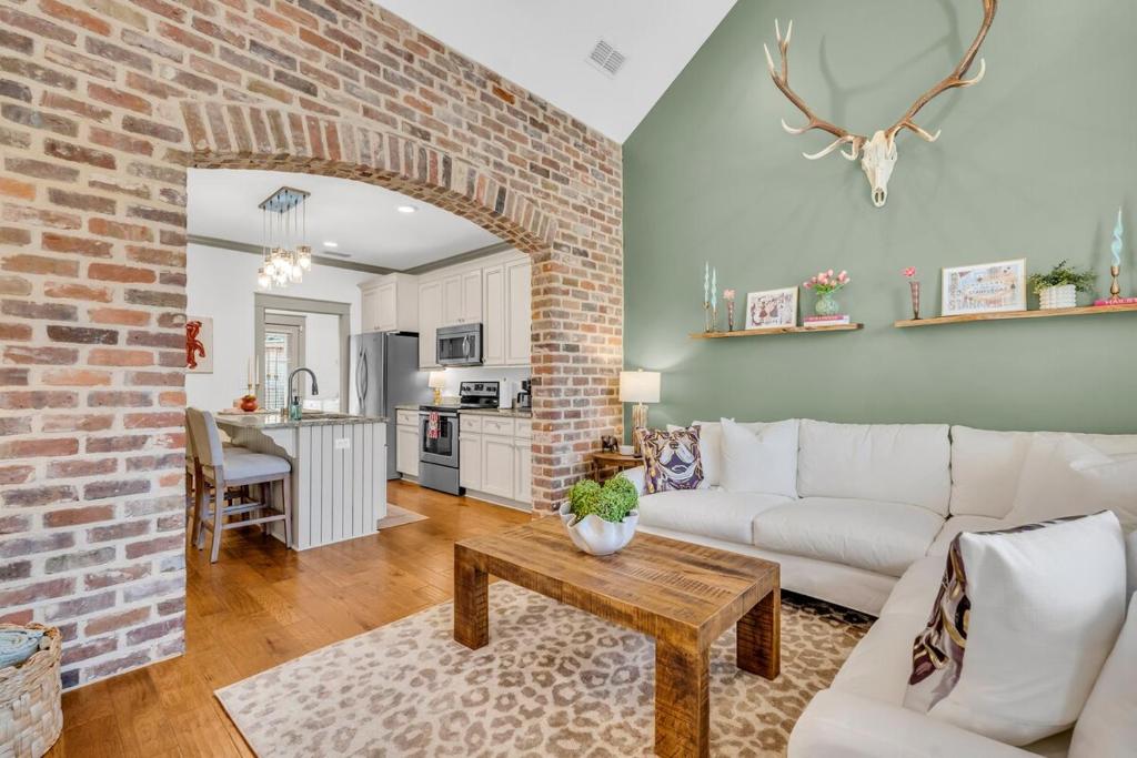 a living room with a white couch and a brick wall at Cowbell Cottage in Starkville