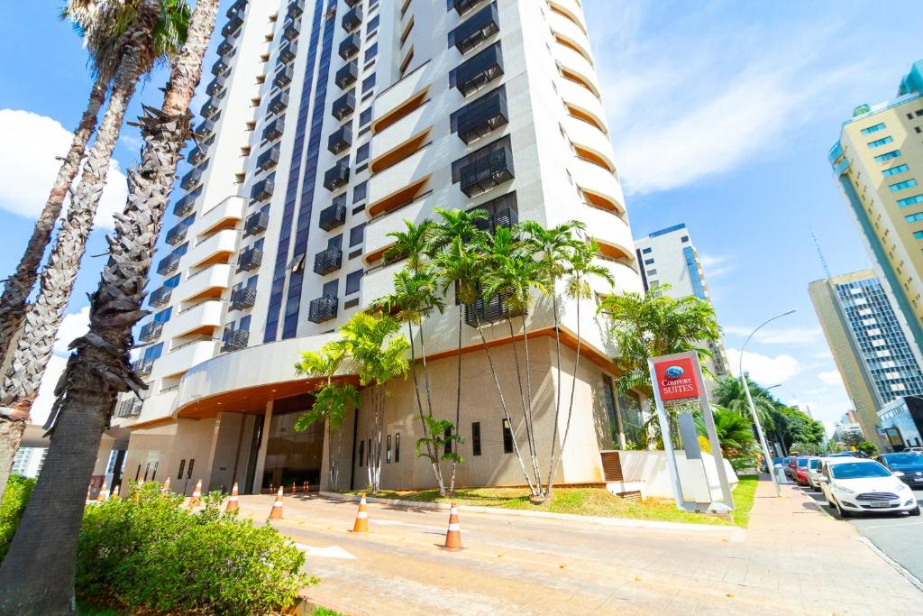 a building with palm trees in front of it at Ozped Private Flats Comfort Suites in Brasília