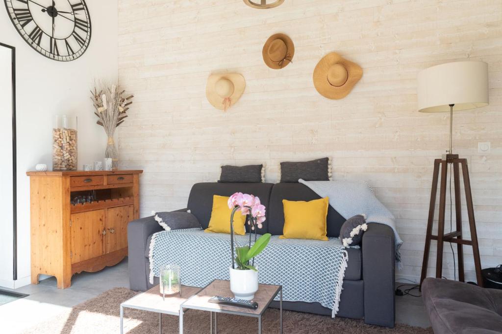 un salon avec un canapé et une horloge au mur dans l'établissement Jolie Maison 84 m2 Océan Bordeaux Médoc Châteaux, à Salaunes