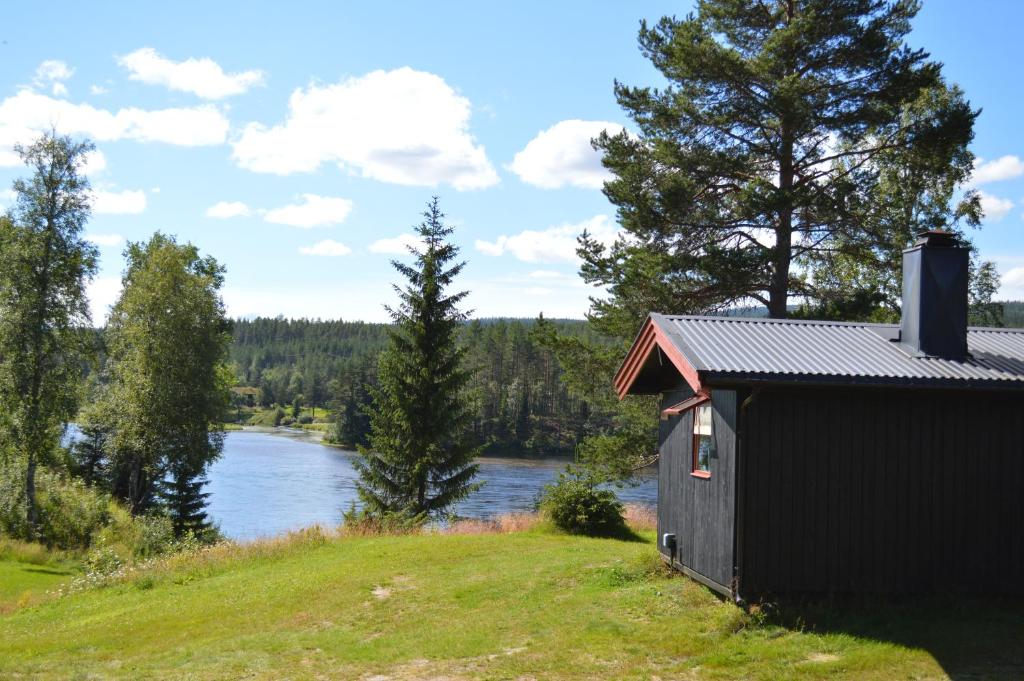 a small black building on a hill next to a river at Trysil Hyttegrend in Trysil