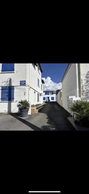 two white buildings with potted plants on a street at Appartement bord de mer in Jullouville-les-Pins