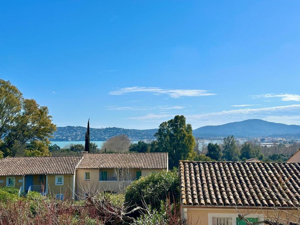 un groupe de maisons avec des montagnes en arrière-plan dans l'établissement À pied à la plage & vue mer, à Grimaud