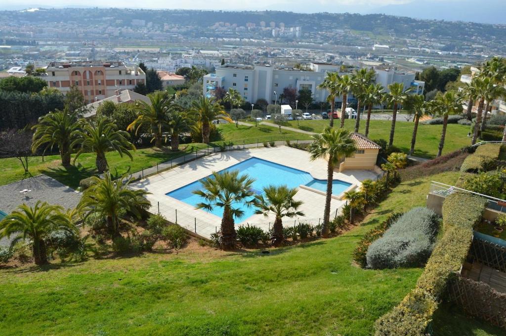 une vue aérienne d'une piscine avec des palmiers dans l'établissement Studio équipé dans une résidence avec piscine à 10mn du centre ville, à Nice