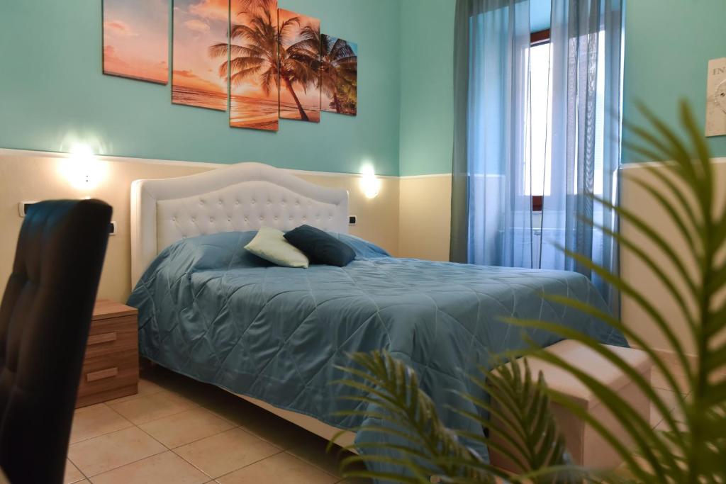 a bedroom with a bed with blue sheets and a plant at "ENCHANTED HOME" Lusso & Solarium a 5 minuti dal PORTO in Civitavecchia