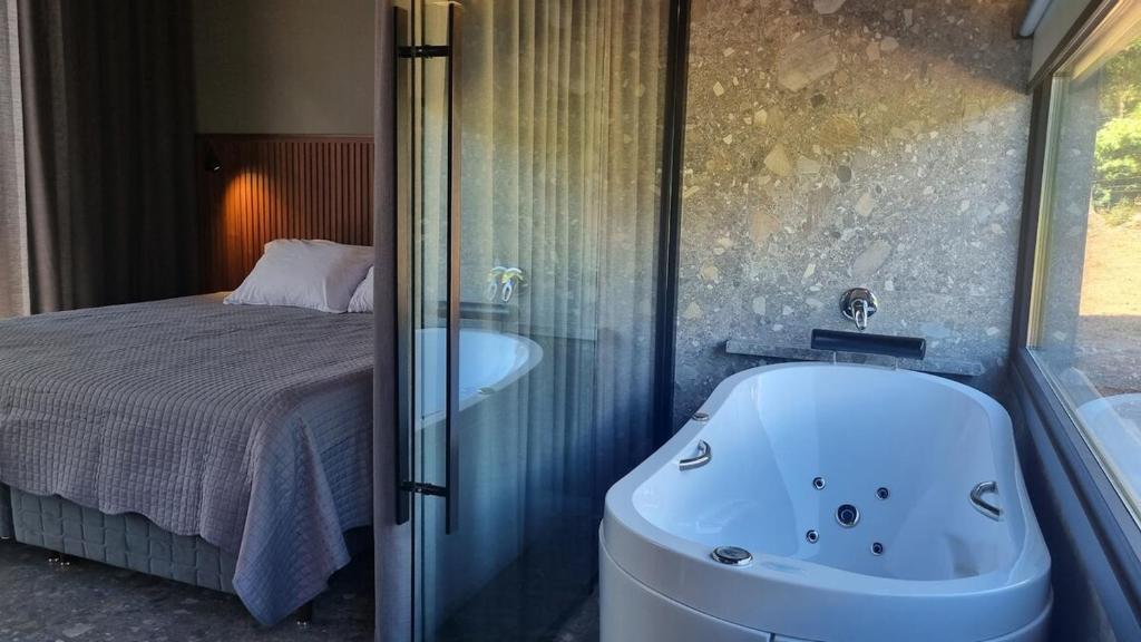 a bathroom with a bath tub next to a bed at TinyWine House Vale dos Vinhedos - Cabana Malbec in Garibaldi