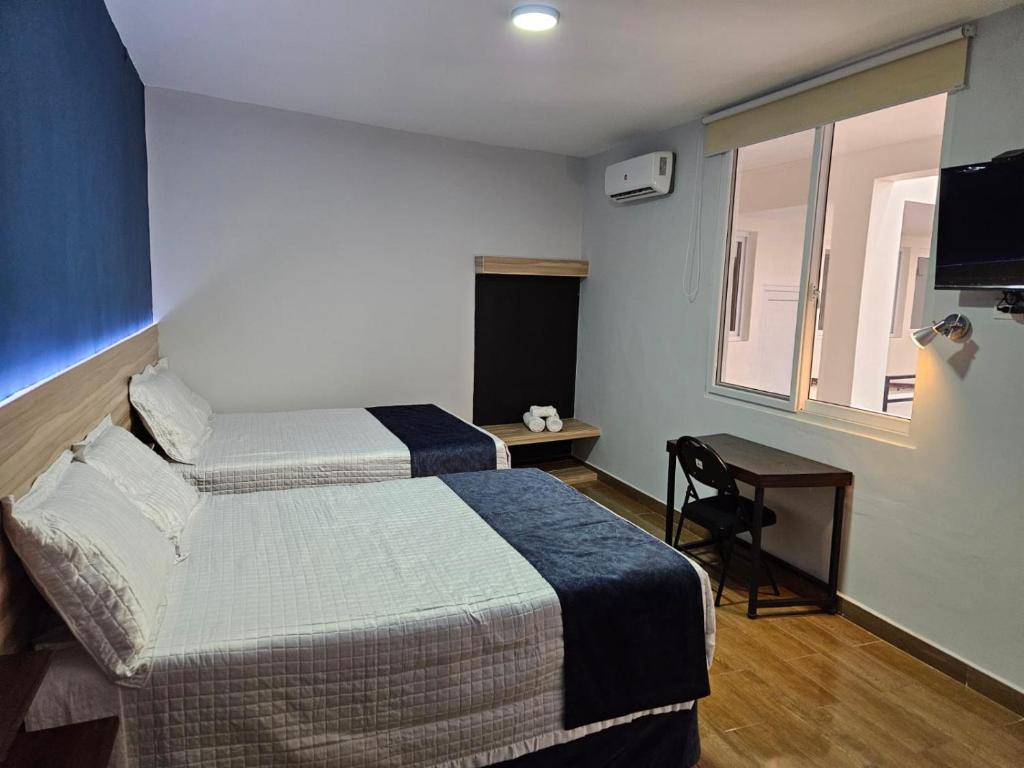 Una habitación de hotel con dos camas y una ventana. en Casa Sismarro Hotel, en Retalhuleu