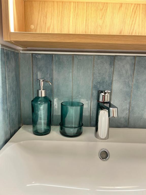 a sink with two glass bottles and a faucet at Oleander Apartment in Agios Georgios