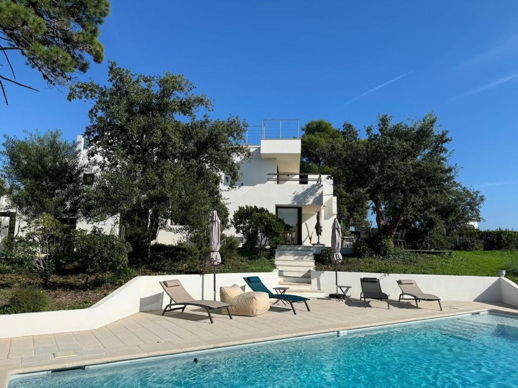 une piscine avec des chaises longues et une maison dans l'établissement Cannes Villa Sea View 5 Bedrooms - Villa Kanupi, à Vallauris