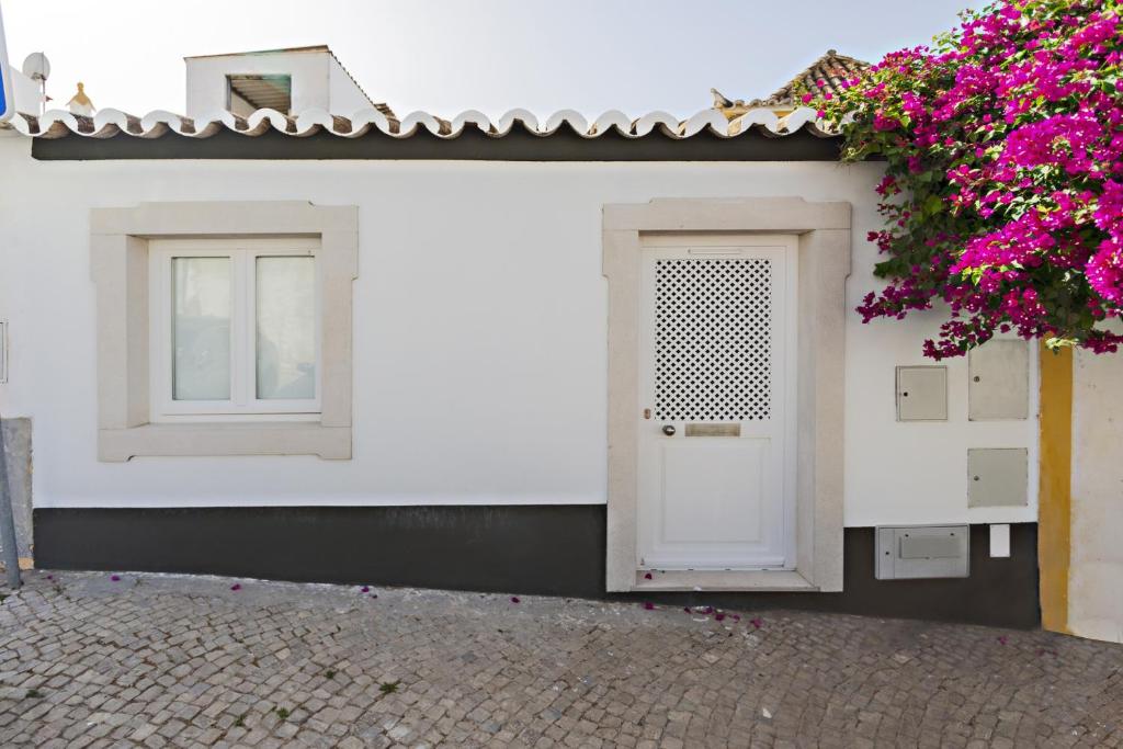 un edificio bianco con una porta bianca e due finestre di Casa do Relógio a Tavira