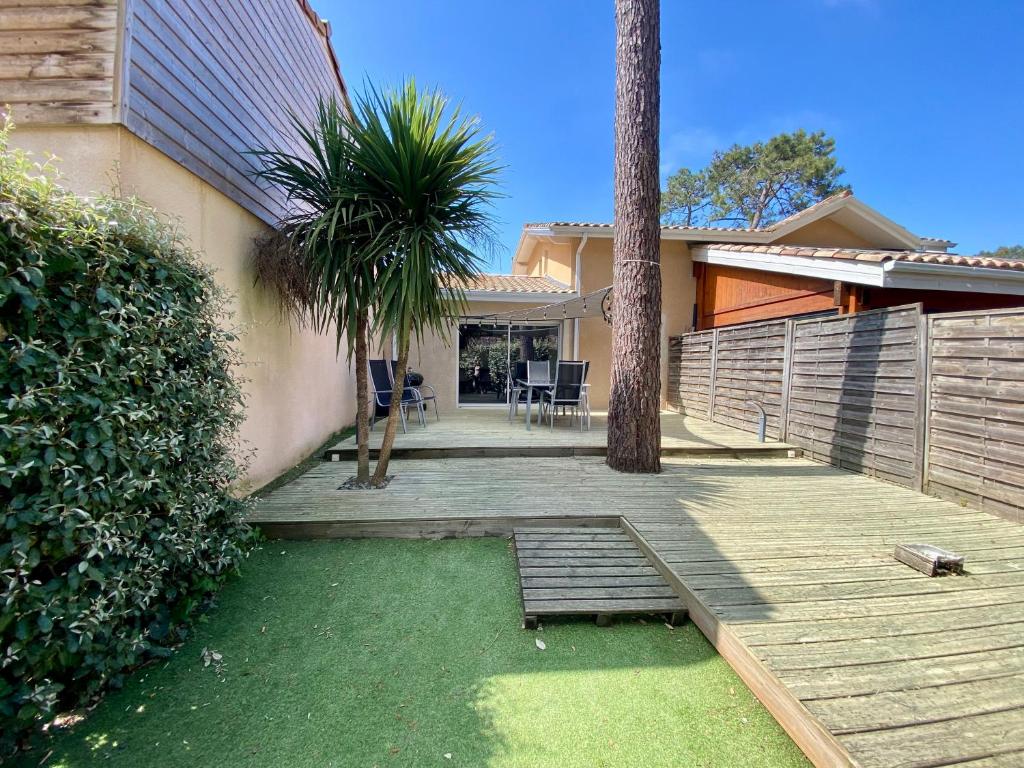 une maison dotée d'une terrasse en bois avec des palmiers dans l'établissement Charmante maison lacanau océan, à Lacanau-Océan